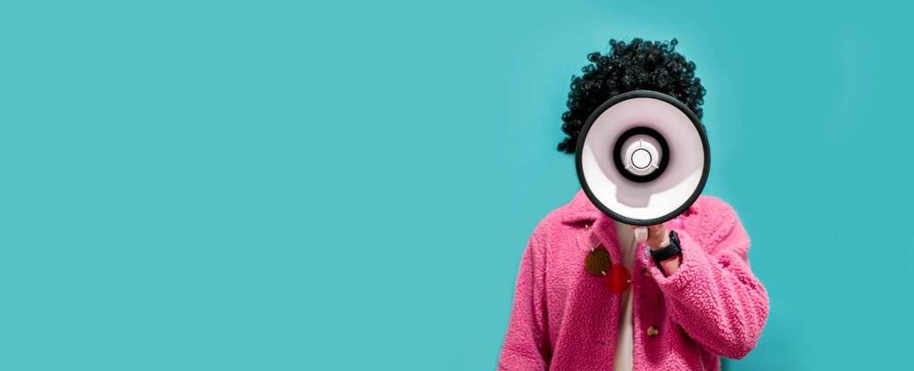 Person standing in front of blue background with loudspeaker